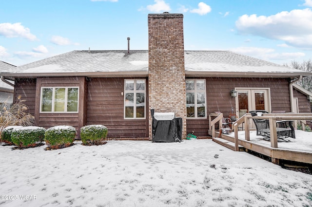 snow covered back of property featuring a deck and french doors