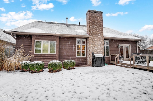 snow covered rear of property with a deck