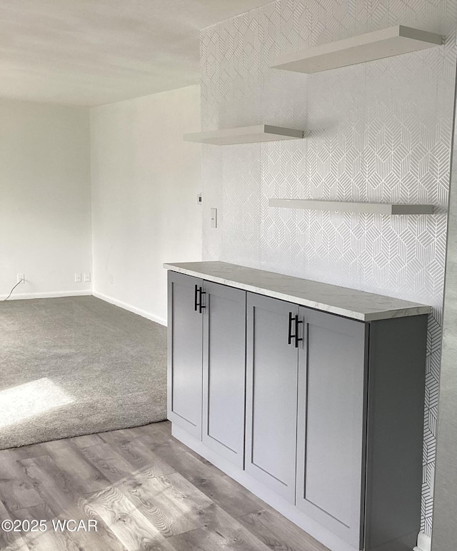 kitchen with carpet floors, light countertops, gray cabinetry, wood finished floors, and baseboards