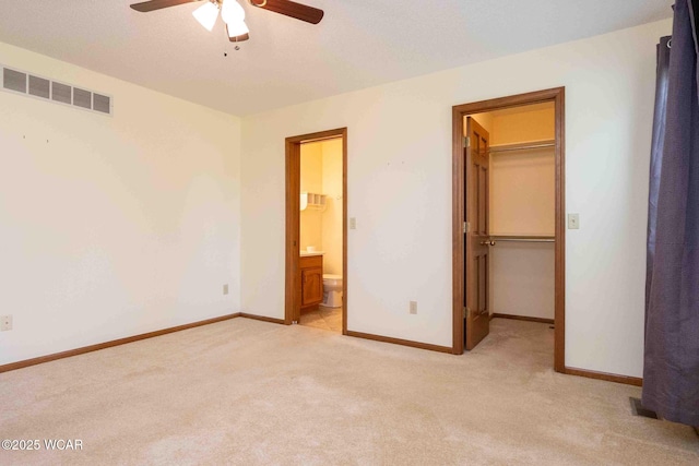 81 Riley Creek Ct, Bluffton, OH 45817 - unfurnished bedroom featuring a walk in closet, light carpet, a closet, ensuite bath, and a ceiling fan