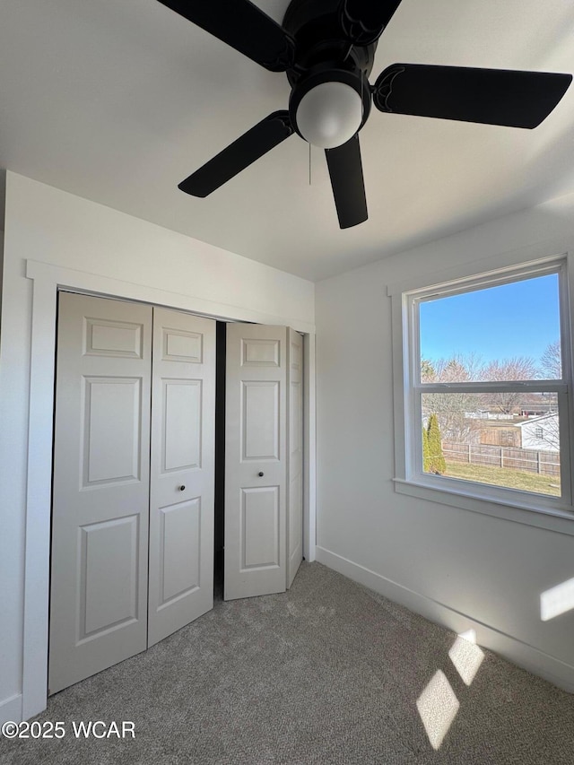 unfurnished bedroom with baseboards, a closet, carpet floors, and ceiling fan