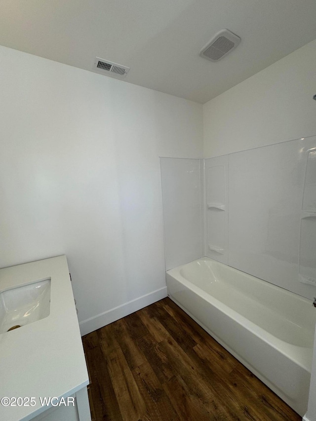 bathroom with a sink, baseboards, visible vents, and wood finished floors