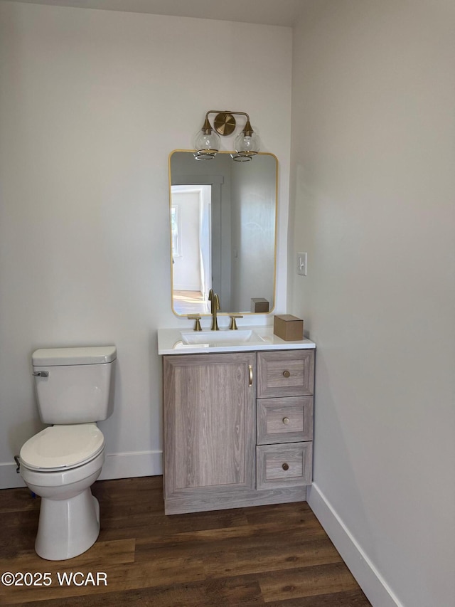 bathroom featuring baseboards, toilet, wood finished floors, and vanity