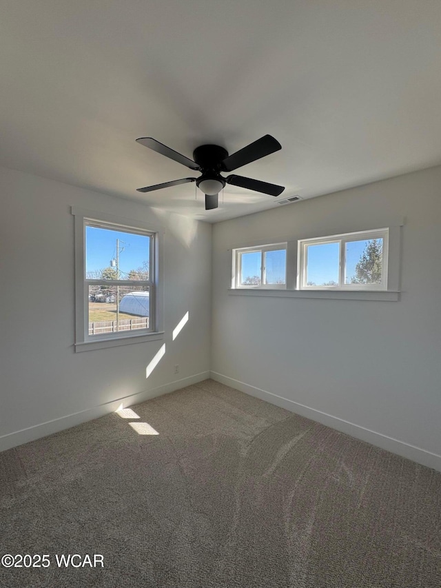 empty room featuring visible vents, carpet, baseboards, and ceiling fan