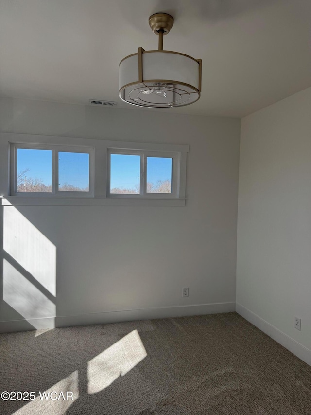 unfurnished room featuring carpet flooring, a healthy amount of sunlight, visible vents, and baseboards