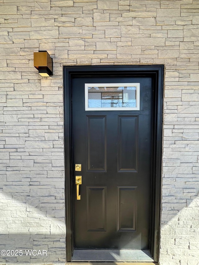 entrance to property featuring brick siding and roof with shingles