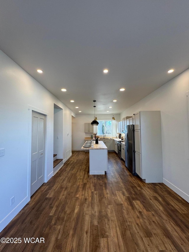 kitchen featuring visible vents, pendant lighting, dark wood finished floors, stainless steel appliances, and light countertops