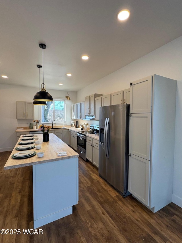 kitchen featuring a sink, a center island, light countertops, stainless steel appliances, and dark wood-style flooring