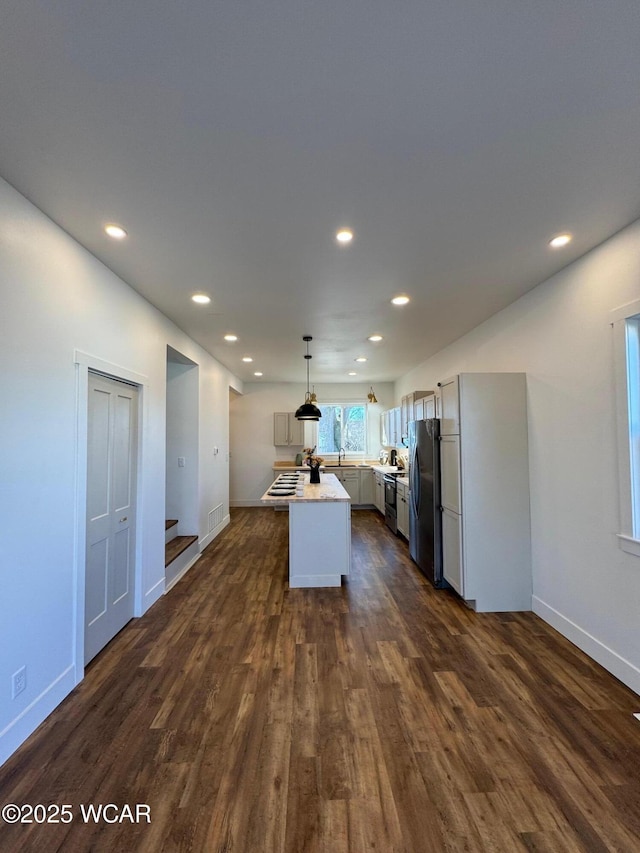 kitchen featuring dark wood finished floors, recessed lighting, stainless steel appliances, light countertops, and decorative light fixtures