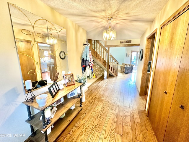 2969 Sands Rd, Lima, OH 45805 - hall with a chandelier, light wood-type flooring, a textured ceiling, and stairs