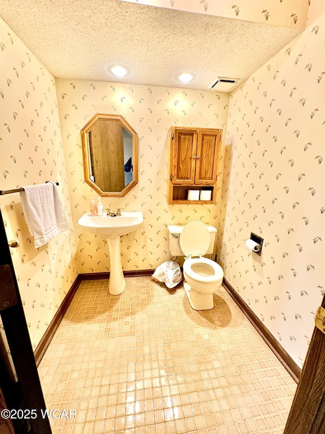 2969 Sands Rd, Lima, OH 45805 - half bathroom with wallpapered walls, toilet, a textured ceiling, and baseboards