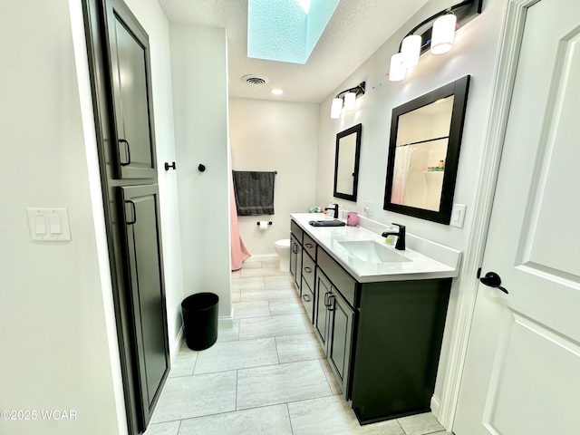 2969 Sands Rd, Lima, OH 45805 - bathroom featuring a skylight, toilet, double vanity, a textured ceiling, and a shower