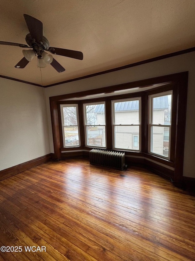 spare room with crown molding, a healthy amount of sunlight, radiator, and hardwood / wood-style floors