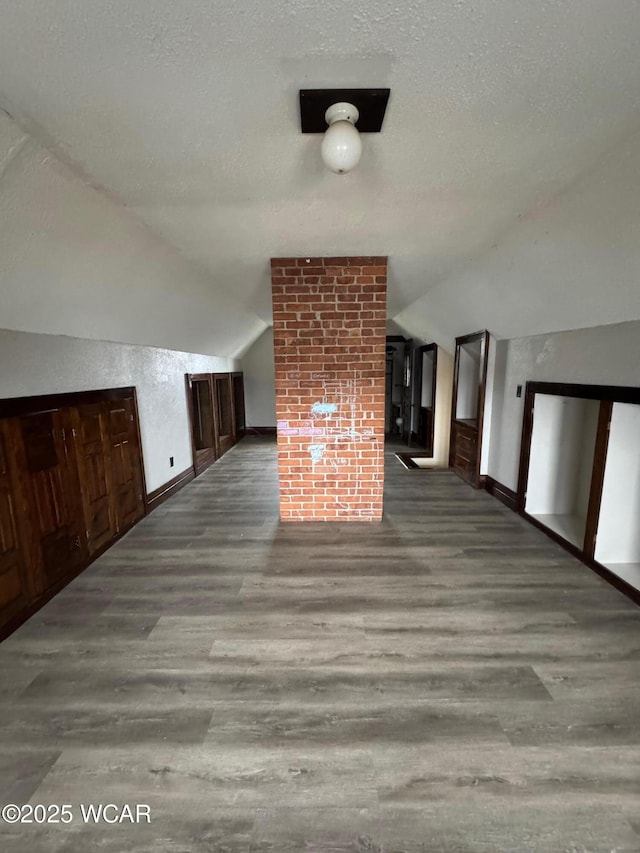 bonus room featuring lofted ceiling, hardwood / wood-style floors, and a textured ceiling