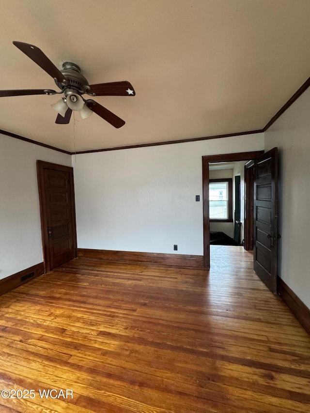 empty room with ornamental molding, wood-type flooring, and ceiling fan