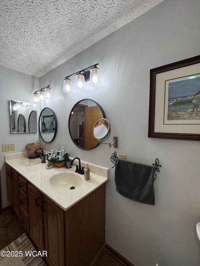bathroom featuring tile patterned floors, double vanity, a textured ceiling, and a sink