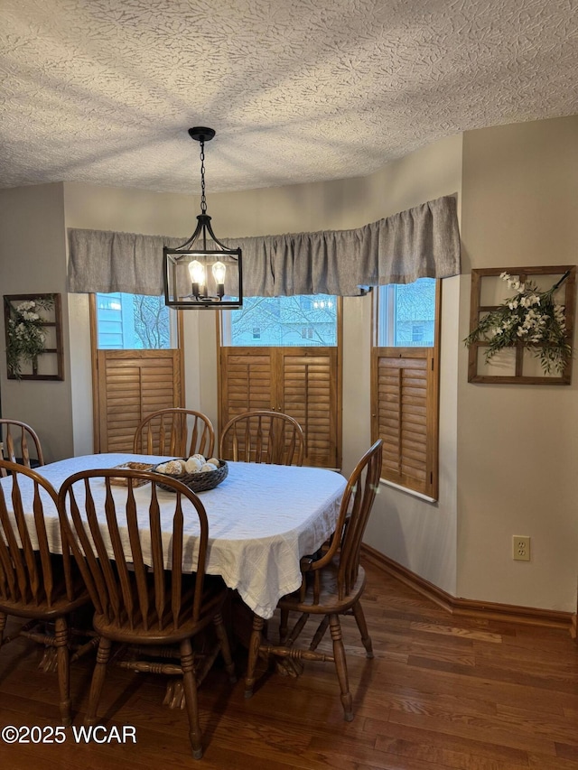 dining area featuring baseboards, a textured ceiling, an inviting chandelier, and wood finished floors
