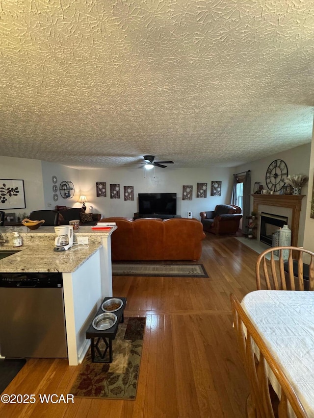 kitchen with a fireplace with flush hearth, a ceiling fan, dishwasher, and dark wood finished floors