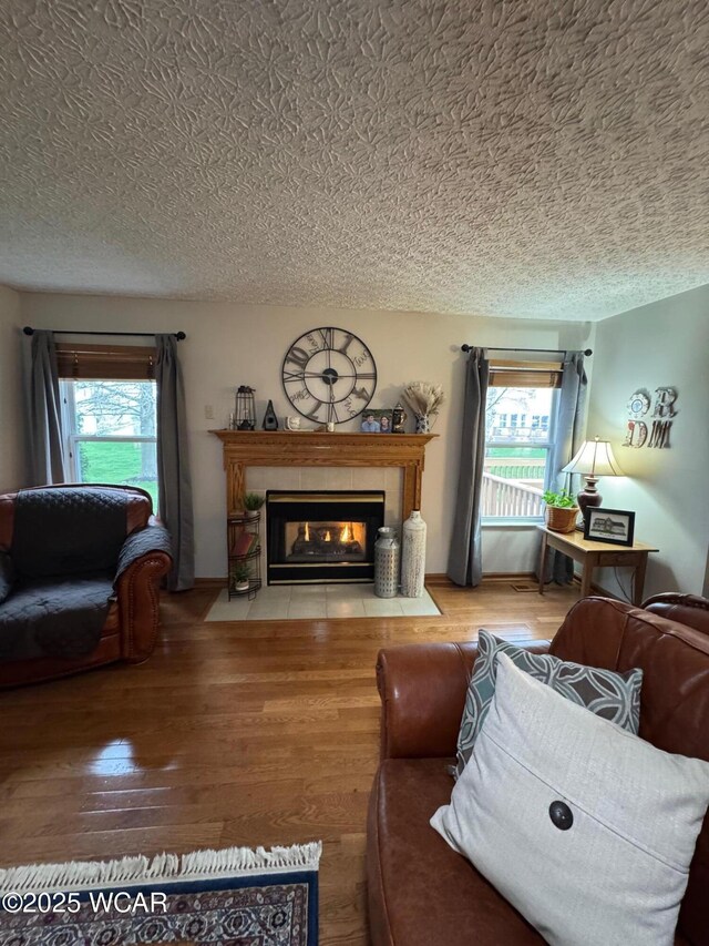 living area featuring a textured ceiling, wood finished floors, and a fireplace