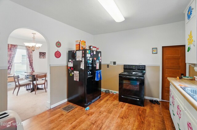 219 W O Connor Ave, Lima, OH 45801 - kitchen with black appliances, a chandelier, arched walkways, light wood-type flooring, and light countertops
