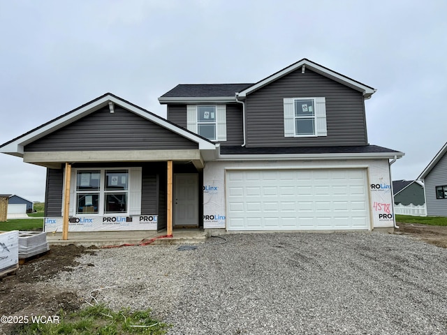 view of front of house featuring covered porch, an attached garage, and gravel driveway