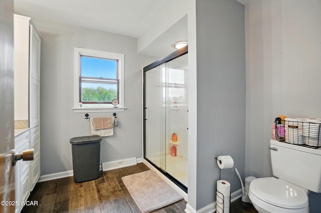 full bathroom with wood finished floors, a shower stall, toilet, and baseboards