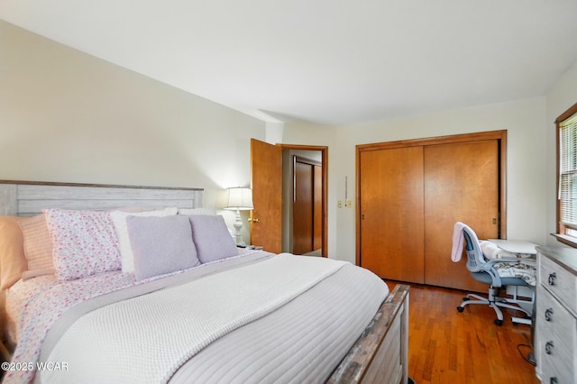 bedroom featuring a closet, an office area, and wood finished floors