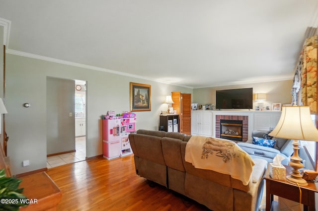 living area with crown molding, wood finished floors, a fireplace, and baseboards