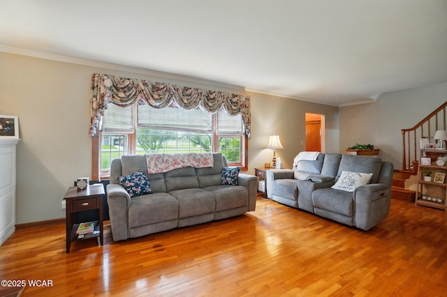 living room with wood finished floors, ornamental molding, and stairs