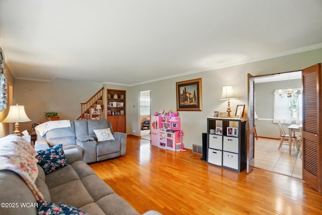 living room with light wood-style floors, a chandelier, stairs, crown molding, and baseboards