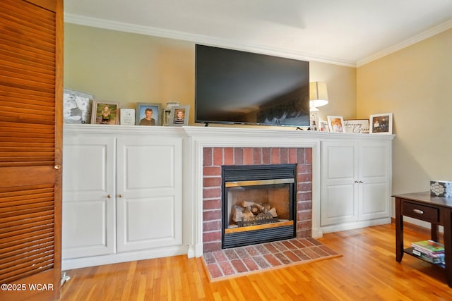 living room featuring crown molding, wood finished floors, and a brick fireplace