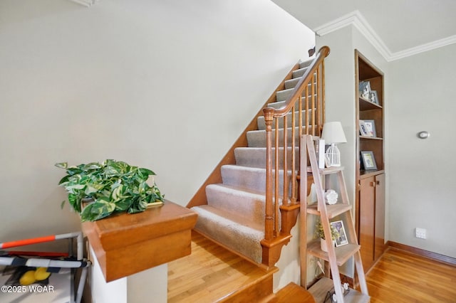 stairway featuring ornamental molding, wood finished floors, and baseboards