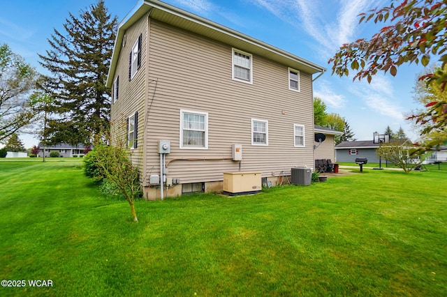 rear view of house featuring cooling unit and a yard
