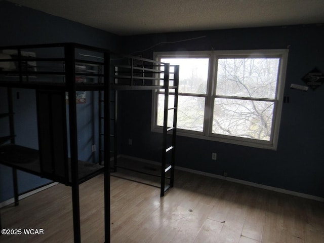 unfurnished bedroom with multiple windows, hardwood / wood-style floors, and a textured ceiling