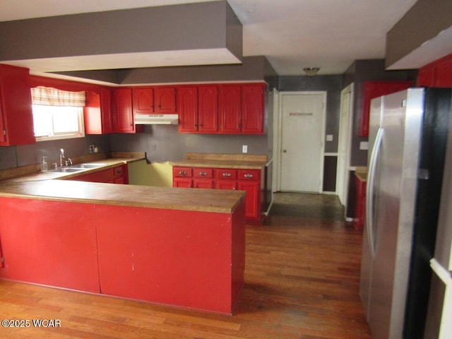 kitchen featuring hardwood / wood-style floors, sink, stainless steel refrigerator, and kitchen peninsula