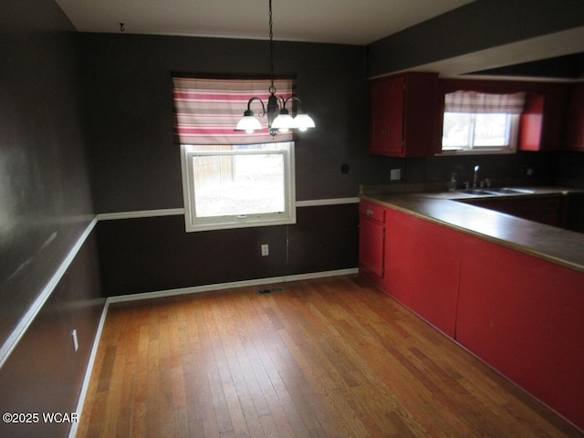 kitchen with sink, a notable chandelier, and light hardwood / wood-style flooring