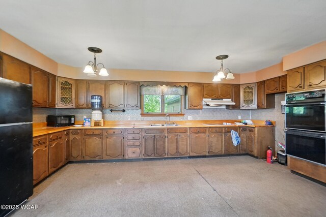 411 W Pattison Ave, Kenton, OH 43326 - kitchen with black appliances, a chandelier, under cabinet range hood, and brown cabinetry