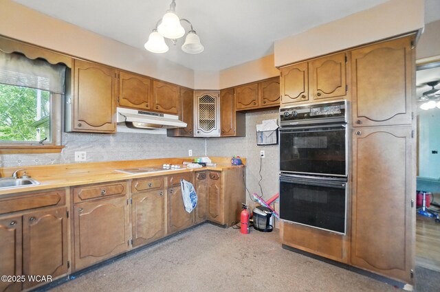 411 W Pattison Ave, Kenton, OH 43326 - kitchen featuring under cabinet range hood, brown cabinets, light countertops, white electric cooktop, and decorative light fixtures