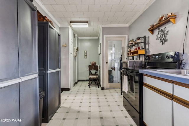 kitchen with light floors, baseboards, ornamental molding, and black range with electric stovetop