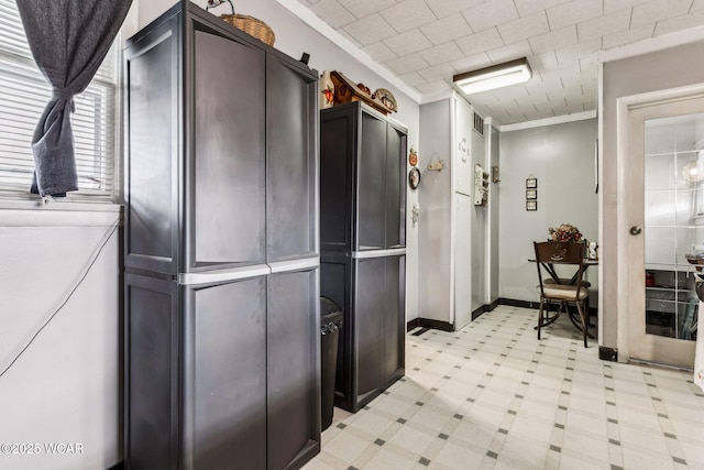 kitchen featuring light countertops, baseboards, crown molding, and light floors