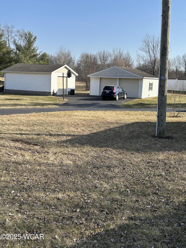 view of yard featuring a detached garage and an outbuilding