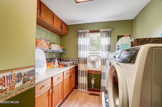 laundry area with visible vents, washer and dryer, cabinet space, and light wood finished floors