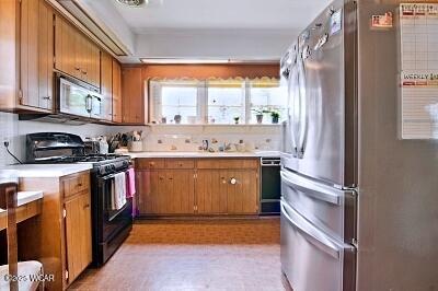 402 S Woodlawn Ave, Lima, OH 45805 - kitchen with black appliances, light countertops, brown cabinetry, and a sink