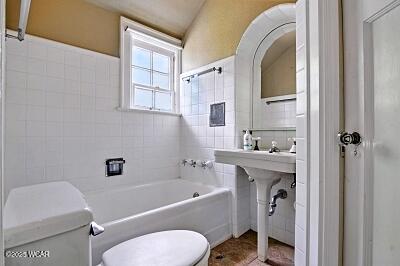 402 S Woodlawn Ave, Lima, OH 45805 - bathroom featuring tile walls, toilet, lofted ceiling, tile patterned floors, and bathing tub / shower combination