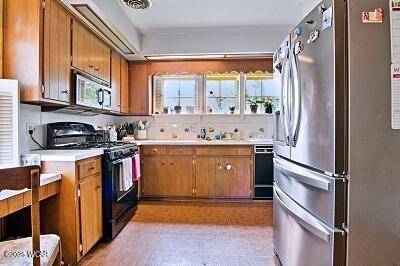 402 S Woodlawn Ave, Lima, OH 45805 - kitchen with black appliances, light countertops, brown cabinets, and a sink