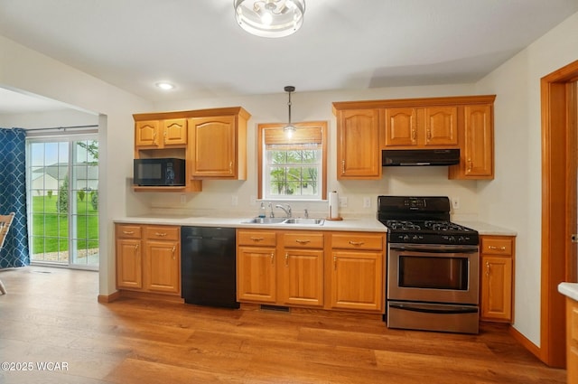 1330 Christina St, Delphos, OH 45833 - kitchen with black appliances, under cabinet range hood, a sink, light countertops, and light wood-type flooring
