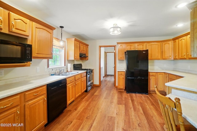 1330 Christina St, Delphos, OH 45833 - kitchen with black appliances, a sink, under cabinet range hood, light wood finished floors, and pendant lighting