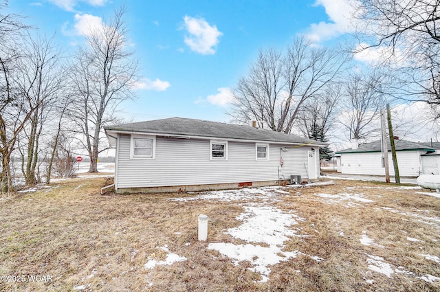 snow covered house with central air condition unit and a yard