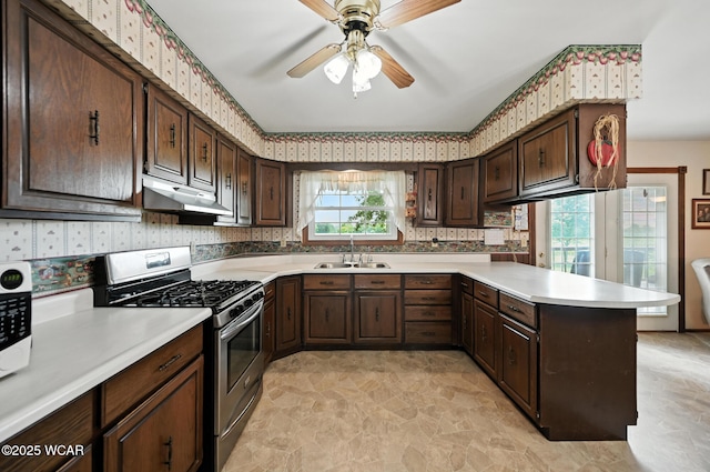 10815 Holdgreve Rd, Delphos, OH 45833 - kitchen with stainless steel gas range oven, a peninsula, a ceiling fan, light countertops, and under cabinet range hood