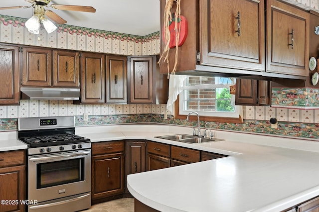 10815 Holdgreve Rd, Delphos, OH 45833 - kitchen with stainless steel gas range, under cabinet range hood, wallpapered walls, light countertops, and ceiling fan